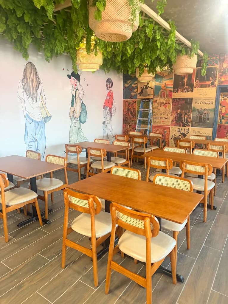 A corner of the dining room with hanging greenery, rattan lanterns and walls collaged in retro Asian movie posters.